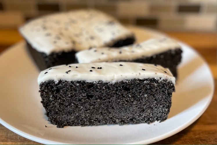 Slices of rich, black sesame chocolate cake fill a white plate.